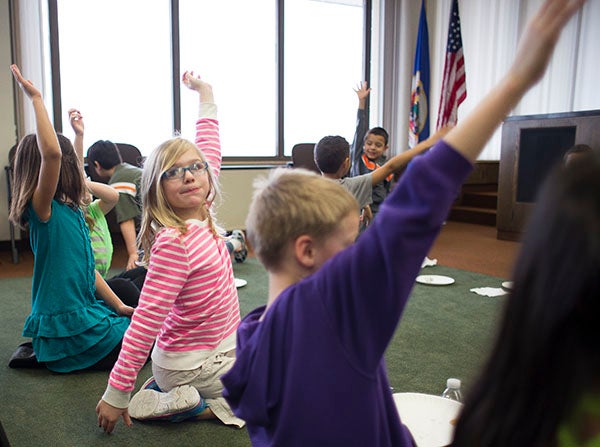 Second-graders from Hawthorne Elementary raise their hands for more pizza during a visit to City Hall on Tuesday for Read Across America Day in Albert Lea. – Colleen Harrison/Albert Lea Tribune
