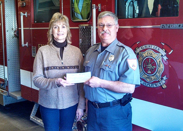 Bill Lehman, secretary and treasurer for the International Association of Firefighters Local 1041 Albert Lea Professional Firefighters, accepts a donation from Jody Adams and the Maple Island Park Association. The donation will help fund the firefighters’ 1st Grade Fire Education Program. The full-time firefighters of the Albert Lea Fire and Rescue Department go to all the first-grade classrooms in District 241 every May to teach students about fire safety. – Submitted