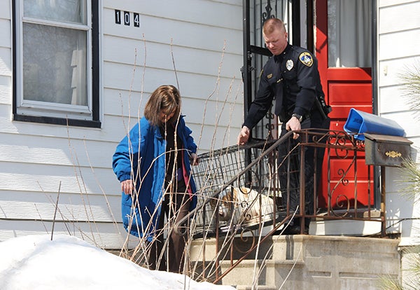 Albert Lea Police Department’s J.D. Carlson, right, and detective Deb Flatness carry a dog down the front stairs of 104 S. First Ave. Wednesday afternoon. Police seized 10 dogs from the home. – Sarah Stultz/Albert Lea Tribune  