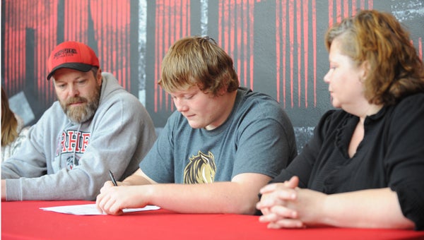 Nic Goette sits between his father, Rod, and his mother, Deb, to sign his letter of intent on Wednesday to play football at Southwest Minnesota State University in Marshall. — Micah Bader/Albert Lea Tribune
