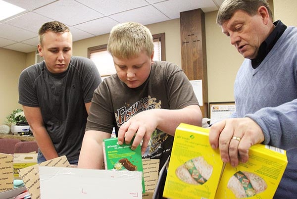 Philipp Wagner, 15, left, and Louis Wagner, 12, help the Rev. Vern Harris pack boxes at New Life Christian Church on Tuesday to send overseas to troops serving in Kabul, Afghanistan. – Sarah Stultz/Albert Lea Tribune