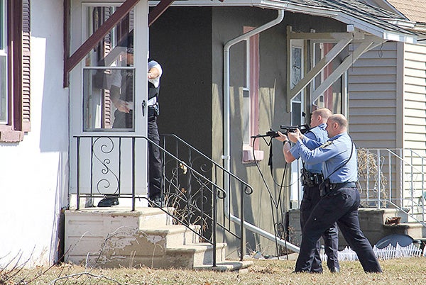 Police enter a home on Ninth Avenue Southwest in Austin with guns drawn Monday. – Jason Schoonover/Albert Lea Tribune