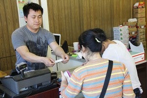 Sei Ko provides change and a receipt to a couple who came to purchase food at Yaw Asian Grocery Store in Albert Lea on Friday. Tim Engstrom/Albert Lea Tribune