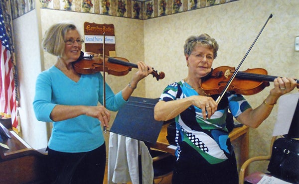 Sharon Astrup-Scott, left, and Eunice Bakken play the violin April 12 for the residents at St. John’s Lutheran Community in Albert Lea. Bakken played “The Palms,” “Just a Closer Walk with Thee” and a few other hymn arrangements. One of the duets played was “In the Garden Alone.” – Submitted