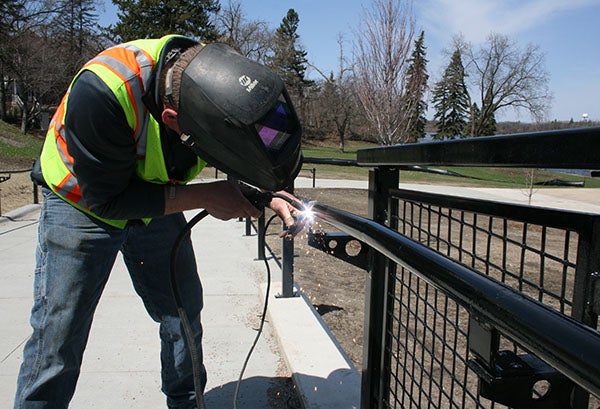 A contractor with White Oak Metals welds a piece of the new railing at Fountain Lake Park Tuesday afternoon. Work at the park is expected to be completed in June. – Sarah Stultz/Albert Lea Tribune