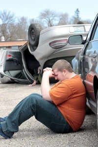 Austin Beseman, a senior at Glenville-Emmons High School, sits beside a Volkswagon Passat Friday during a mock crash at the school. Beseman played the role of a distracted driver who caused the fatal rollover of a Pontiac Grand Prix with three occupants. -- Brandi Hagen/Albert Lea Tribune