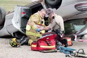 Shawn Willaby, a Glenville firefighter, and Scott Crabtree, a state trooper, give medical attention to McKenna Cech during a demonstration. In the mock crash, Cech was the driver of a Pontiac Grand Prix which was rear-ended by a distracted driver injuring two and killing one. -- Brandi Hagen/Albert Lea Tribune