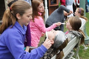 Halverson Elementary School student Shelby Hanson, left, pretends to shave the face of student Mallory Luhring on Wednesday at the Freeborn County Historical Museum, Library & Village. – Sarah Stultz/Albert Lea Tribune