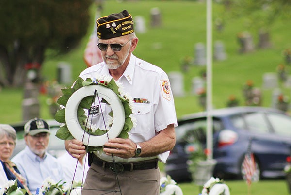Larry Weigel with the Veterans of Foreign Wars Post 447 carries a wreath to be placed in front of a memorial at Graceland Cemetery in Albert Lea on Monday. – Sarah Stultz/Albert Lea Tribune