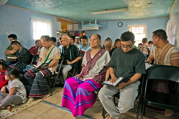Members of the local Karen community attend a Sunday worship service in a Stoney Creek Estates trailer July 13. About 75 people attend the service each week, and Tha Htaw hopes to take down a wall within the trailer to provide more room. – Colleen Harrison/Albert Lea Tribune