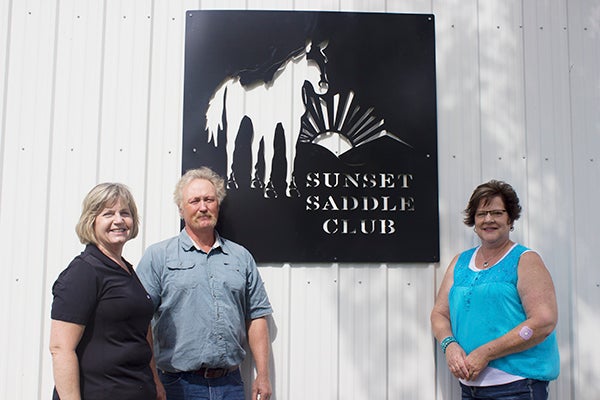 Cindy Farr, far left, and Laverne Jensen, middle, of Lou-Rich stand with Bernice Mattson, right, of the Sunset Saddle Club in front of a steel sign that Lou-Rich donated to the saddle club. — Hannah Dillon/Albert Lea Tribune