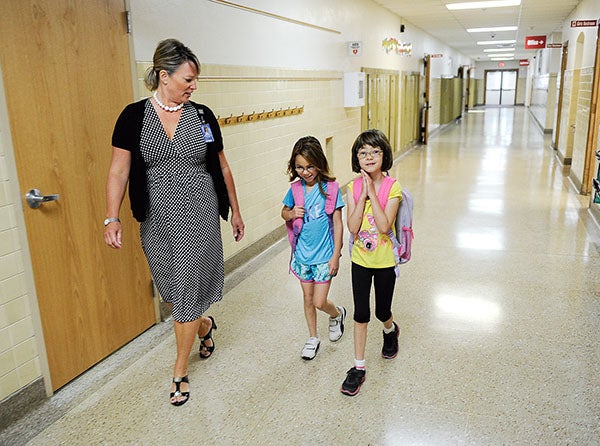 Sumner Elementary School Principal Sheila Berger leads sisters Lilly, right, and Lyla Thompson to their classroom on the first day of school this morning. The Austin school starts earlier than most in Minnesota because it has a schedule of 45 days on and 15 days off. Albert Lea Area Schools are considering a similar schedule that would start in 2015 after the Freeborn County Fair. – Eric Johnson/Albert Lea Tribune