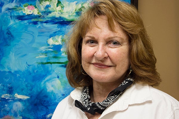 Marty Shepard is the artistic director of the Albert Lea Art Center and has a few pieces in the “Envision the Impressionist” exhibit. She stands in front of her acrylic painting “Earth, Wind, Water.” – Hannah Dillon/Albert Lea Tribune