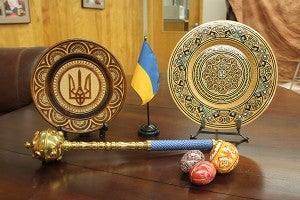 The flag of Ukraine is yellow and blue, representing wheat and sky. Surrounding it are artifacts from Ukraine: plates, a sceptor and eggs. All the decorations are loaded with symbolism. The gold trident in the center of the plate on the left is the coat of arms of Ukraine. – Tim Engstrom/Albert Lea Tribune