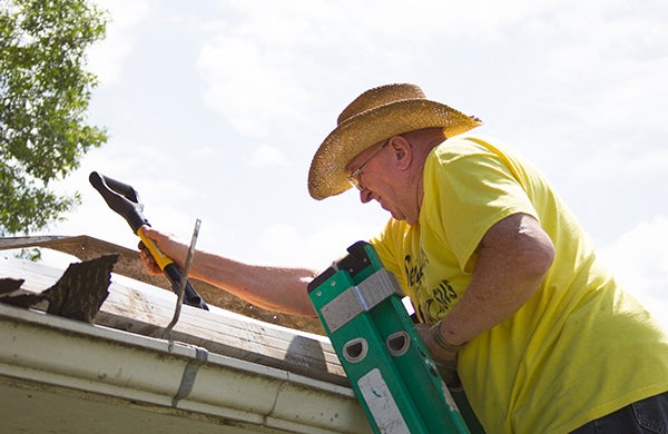 Rick Burrows works on the roof of a garage on Frank Hall Drive as part of Shinefest in August 2014. – Sarah Stultz/Albert Lea Tribune