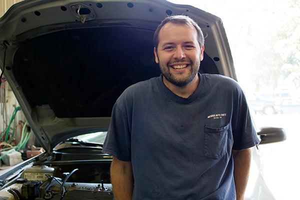 Daniel Misgen leans against a car in the garage of Misgen Auto Parts in Ellendale. — Hannah Dillon/Albert Lea Tribune