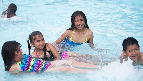 From left, Anahi Castissa Lazaro, 8, Stephanie Lazaro, 6, Evelin Perez Peralta, 11, and Anthony Castissa, 7, play together and smile for the camera in June at the Albert Lea city pool. – Colleen Harrison/Albert Lea Tribune