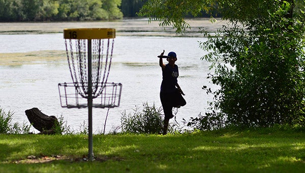 A disc golfer putts on Hole 16 of Oak Island Disc Golf Course from the edge of the water of Bancroft Bay last August when Bancroft Bay Park hosted the Minnesota State Disc Golf Championships. – Buck Monson/Buck Monson Photography