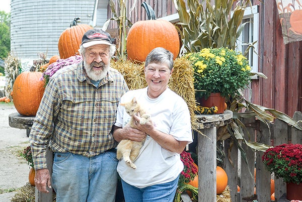 Farmer John and wife Jan stand at their pumpkin patch Tuesday evening. – Jenae Hackensmtih/Albert Lea Tribune