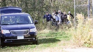 A body, found Saturday morning in the wooded area west of the Riverland Community College, is carried to a waiting van. – Eric Johnson/Albert Lea Tribune