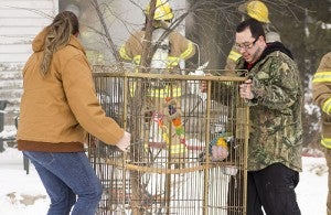 Katie Hallman, left, and Marcelino Talamantes carry a pet parrot away from 248 N. Broadway in Alden on Tuesday as firefighters put out a fire at the house. — Sarah Stultz/Albert Lea Tribune