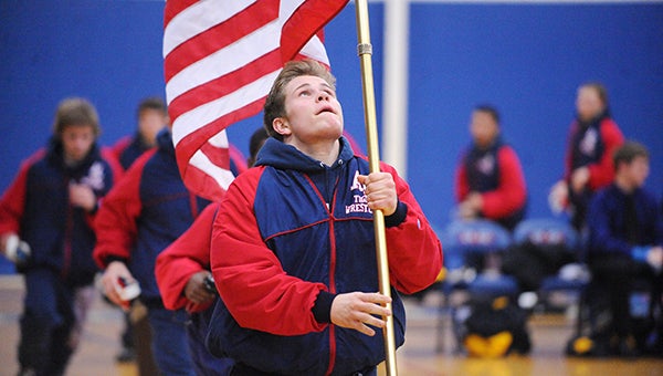 Tim Christianson of Albert Lea carries the American flag as he leads the team around the mat Thursday on Freedom Night against Byron at Albert Lea. — Micah Bader/Albert Lea Tribune