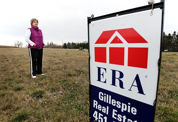 Ginny Busch, mayor of the city of Claremont, stands in a empty lot that was intended to be someone’s home. – Alex Kolyer/Minnesota Public Radio News