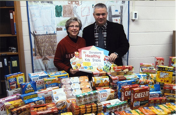 Karen Cibert from the American Legion Auxiliary Unit 56 presents Superintendent Mike Funk with 128 pounds of healthy kids' snacks Nov. 17 during National Education Week. — Provided