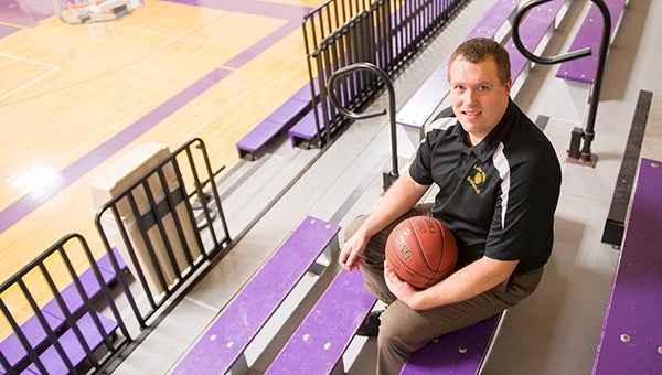 Lake Mills boys’ basketball coach Kyle Menke sits on a bench in the gym at Lake Mills High School. Menke is the Tribune’s All-Area boys’ basketball Coach of the Year. — Colleen Harrison/Albert Lea Tribune