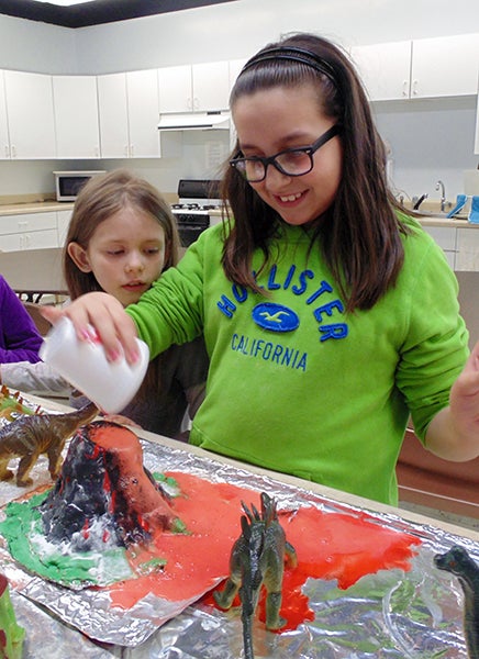 The third-grade students of St. Casimir’s School in Wells recently finished reading their story of Pompeii, “Buried Alive!” After learning how the ancient Roman city was destroyed and buried under 13-20 feet of ash and pumice in the eruption of Mount Vesuvius, the students decided that it would be exciting to build their own exploding volcano during a recent science experiment. The students made their own clay volcano and added baking soda, vinegar and pop rocks to create a popping volcanic eruption.  The project was a wonderful mix of science, curiosity, art and good old fun as shown when Destiny Chavez’s volcano spewed forth under the watchful gaze of Brooklyn Miller. -Provided