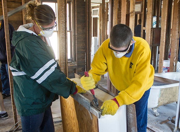 Thomas Wear, right, removes nails from a board on Wednesday at the former Hotel Washburn as Emily Schultz assists. Students from NRHEG are volunteering for demolition and renovations of the building as part of a class. - Sarah Stultz/Albert Lea Tribune