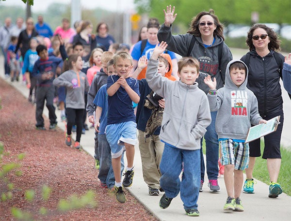 Students from Hawthorne Elementary School wave as they participate in a walkathon Friday. — Colleen Harrison/Albert Lea Tribune
