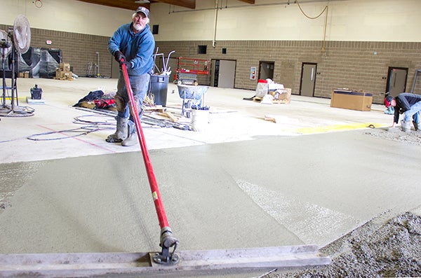A contractor smooths out concrete in the gym of the National Guard Armory in Albert Lea on Tuesday. Some squares of concrete are being replaced as part of a larger renovation at the armory. - Sarah Stultz/Albert Lea Tribune