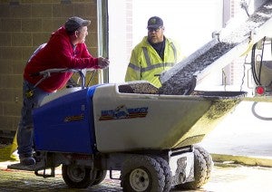 Two contractors talk as cement is poured in preparation for the floor at the Albert Lea National Guard Armory. - Sarah Stultz