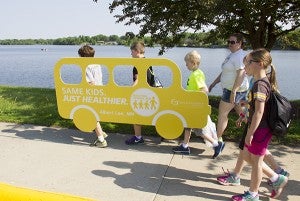 St. Theodore Catholic School students carry a Blue Zones Project walking school bus cutout as they walked around Fountain Lake on Wednesday. - Sarah Stultz/Albert Lea Tribune