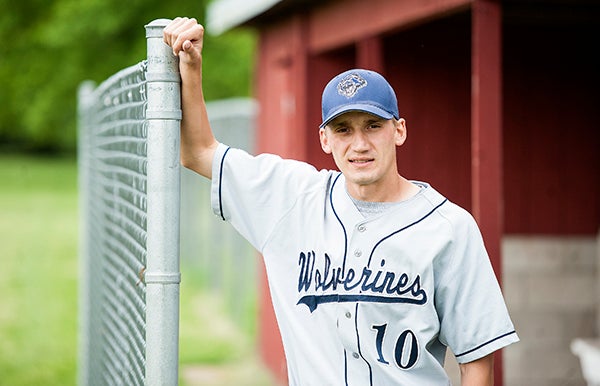 Lucas Knutson leans on the fence in front of a dugout on May 29 at the Glenville-Emmons baseball field. Knutson is the Wolverines’ JV baseball head coach. -Micah Bader/Albert Lea Tribune