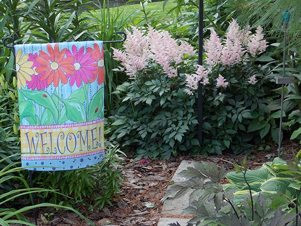 A sign and blooming pink astilbe welcome visitors to the gardens. - Carol Hegel Lang/Albert Lea Tribune
