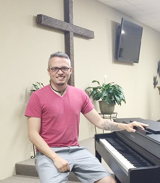 Nick Roen sits on the piano bench at Sojuners Church in Albert Lea. The piano is one of the four insturments Roen can play. - Madeline Funk/ Albert Lea Tribune 