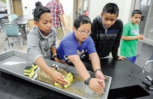 Andrew Hernandez, from left, Leon Kong and Yahir Amador, all from Albert Lea, go over ideas on how to make their experiment in flood control better during Project E3 Thursday at I.J. Holton Intermediate School. - Eric Johnson/Albert Lea Tribune