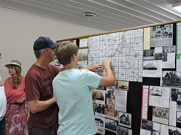 Cory Bauers of rural Clarks Grove looks at a map displayed at the Clarks Grove Historical Museum with his son, Nathan, that shows the various schools which have existed in the area. - Kelly Wassenberg/Albert Lea Tribune