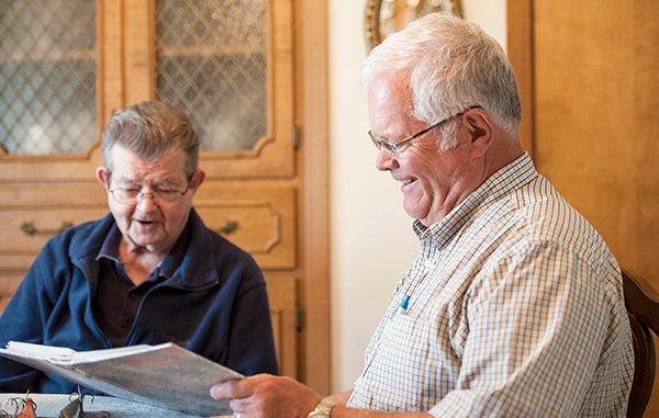 Bob Goldman, right, and Chuck Lee look through an album of fishing photos and reminisce about trips they took together. - Micah Bader/Albert Lea Tribune