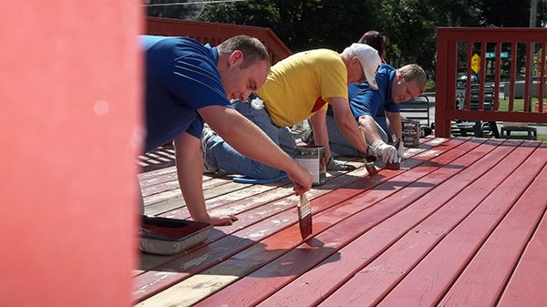 Volunteers paint a deck during Shinefest. -Provided