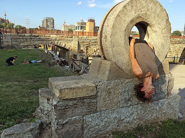 During a performance of “Closer” on Aug. 7, Otto Ramstad used an old millstone in Mill Ruins Park in Minneapolis as a prop during a one-to-one performance. Behind him, dancer Anna Marie Shogren laid prone as she performed for Rachel Jendrzejewski. At any point three or four “Closer” performances were happening in one place. -Euan Kerr/MPR News