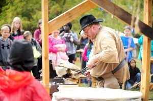 John Debnam of the Twin Cities area teaches sixth-grade students from Owatonna about blacksmithing at Bancroft Bay Park in 2013. - Brandi Hagen/Albert Lea Tribune
