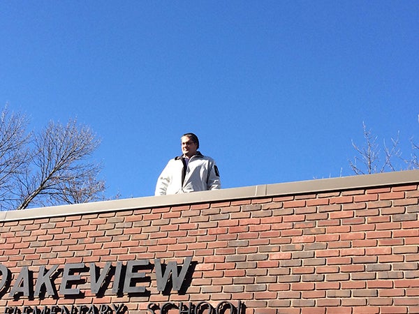 Lakeview Elementary School Principal Nick Sofio stands near the edge of the roof at the school on Thursday. Sofio had his desk on the roof for the whole day as part of the prize for the students reaching their walkathon goal earlier this month. The students could choose whether they wanted him to kiss a pig, get duct-taped to a wall or have his desk on the roof. - Provided