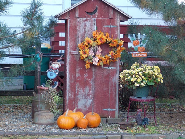 The outhouse is decorated for fall with pumpkins and a colorful wreath as well as a yellow begonia. - Carol Hegel Lang/Albert Lea Tribune