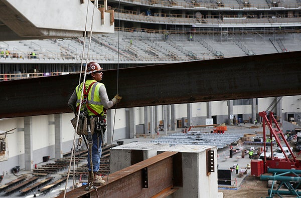 A worker guides a metal beam during construction of U.S. Bank Stadium on July 20. - Jeffrey Thompson/MPR News