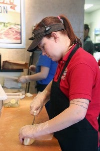 Erbert & Gerbert’s employee Sarah Porter cuts into some bread on Thursday at the business. - Sarah Stultz/Albert Lea Tribune