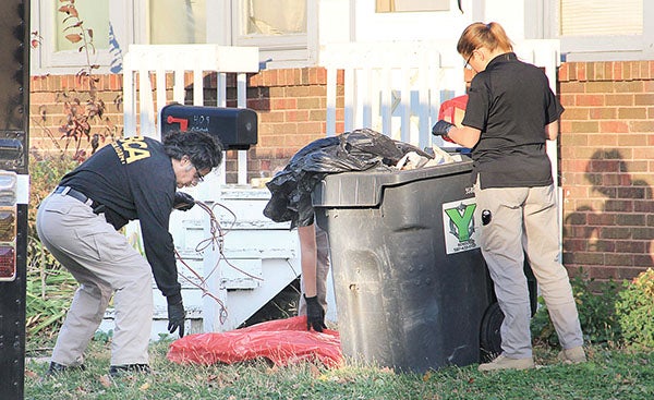 Investigators with the Minnesota Bureau of Criminal Apprehension take evidence from a trash bin outside a home on the 400 block of South Main Street in Austin on Thursday. - Jason Schoonover/Albert Lea Tribune