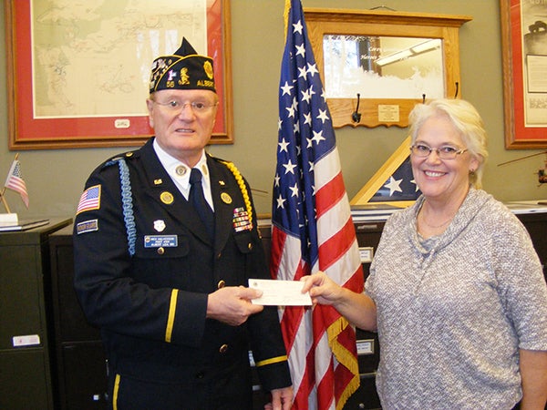 In honor of Veterans Day, the Albert Lea Lions donate $75 to the color guard at the American Legion. Lion Irene Anderson presents the check to Wes Halverson. - Provided
